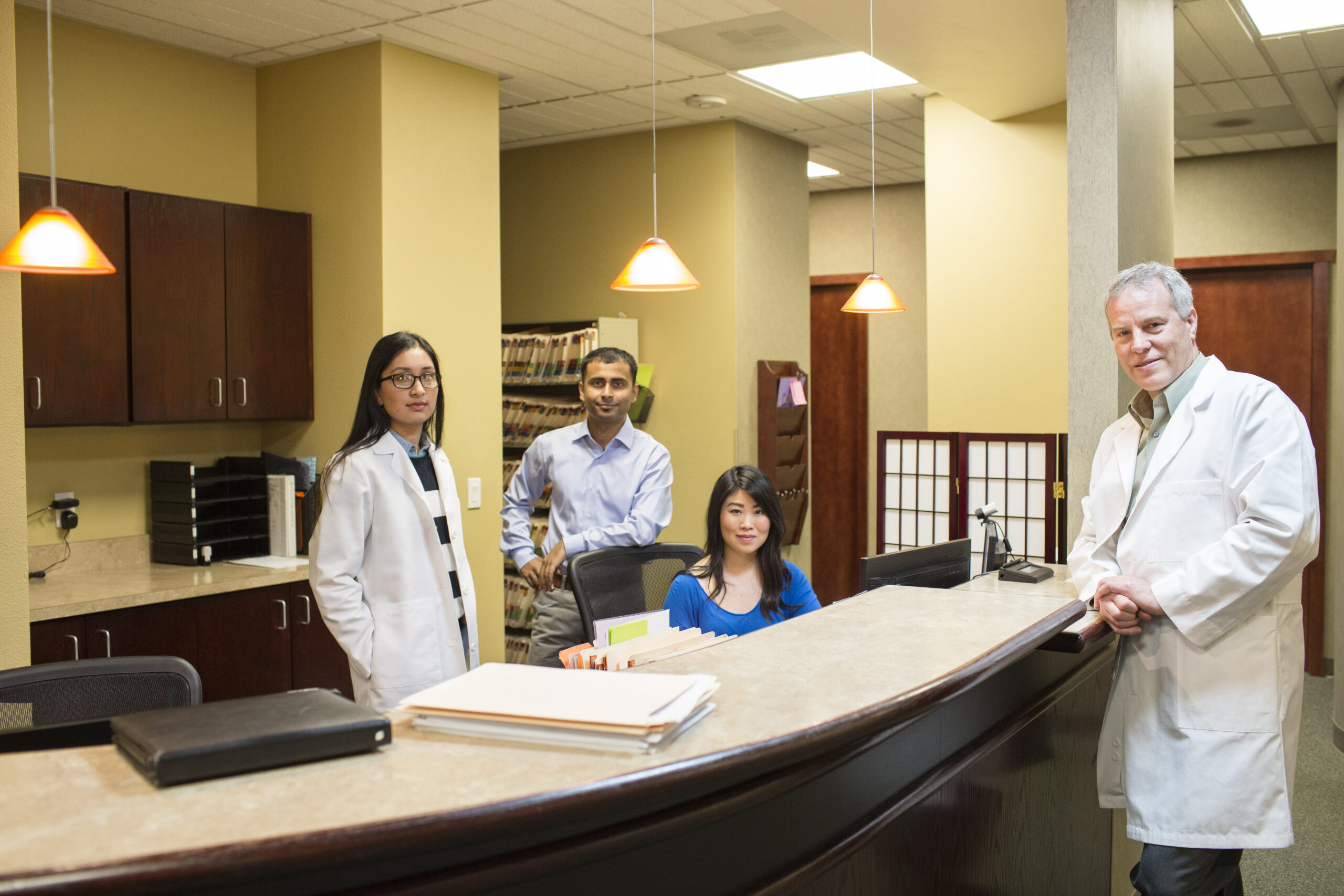 Caucasian male and east Indian woman ophthalmologists in their office with their staff employees.,USA
